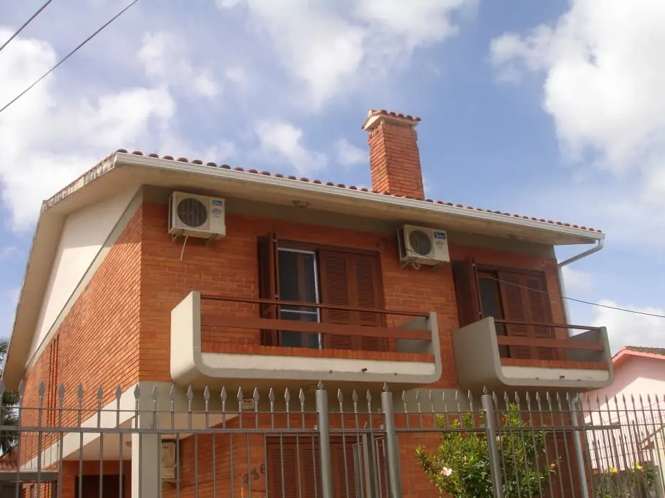 Depois: sobrado de tijolo com calha nova branca, inteira, ao longo do beiral
