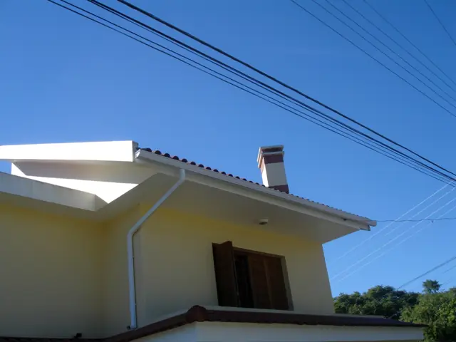 Calha branca no beiral contra o céu azul