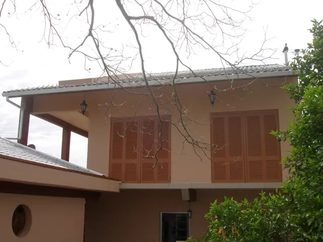 Sobrado com janelas de madeira e calha no beiral